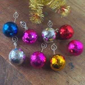 Set of eight colorful 1970s faceted metallic disco ball Christmas baubles arranged on wooden table.